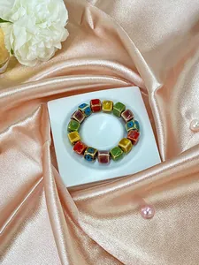 Detail showing square ceramic beads in multiple colors on a luxurious silk background