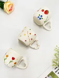 Detailweergave van keramische mokken met hartvormige oren en handgeschilderde bloemen