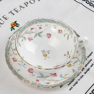 Vista dettagliata dall'alto di tazza e piattino in ceramica con fiori e bordi dorati ondulati