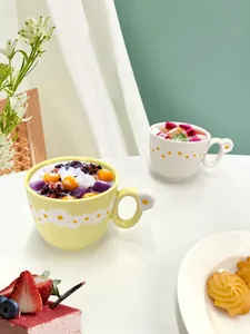 Detail of embossed daisy ceramic mug with flower handle for coffee or breakfast