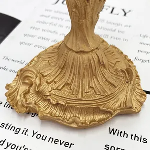 Close-up of golden baroque candle holder base with intricate leaf relief and matte finish