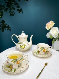 Detail of vintage ceramic teapot and cups set with lemon pattern and gold-rimmed edges