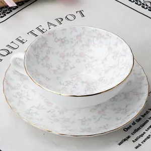 Dettaglio del set tazza da tè e piattino in ceramica con motivi floreali e bordo dorato
