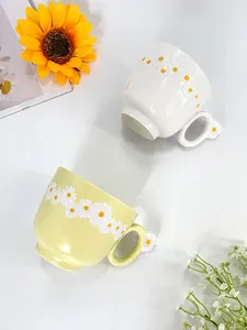 Detail of ceramic daisy coffee mugs with 3D floral accents and glossy glazed finish