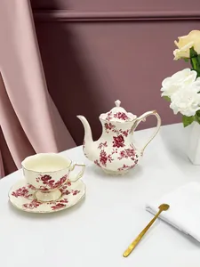Dettaglio macro del set da tè in ceramica crema con rose rosse e bordi dorati fini