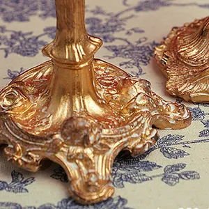 Close-up of golden Baroque candle holder base with intricate floral embossed details