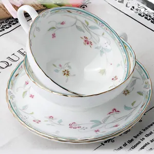 Dettaglio tazza in ceramica floreale con bordo dorato e fiocco fatto a mano su vassoio