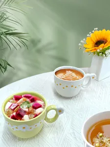Detail of ceramic daisy mug with embossed white petals and yellow centers in green