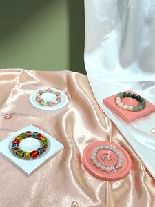 Flat lay of colorful ceramic beaded bracelets and silver ring on silk display stands