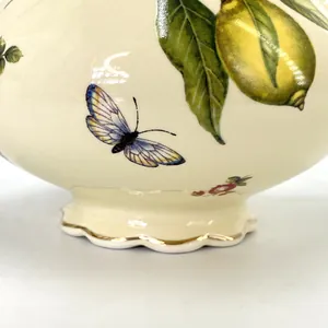 Detailed close-up of lemon and butterfly patterns on a vintage ceramic teapot with gold trim