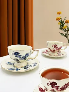 Dettaglio di una tazzina da caffè vintage in ceramica floreale con bordo dorato e piattino