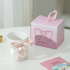 Dettaglio della tazza in ceramica bianca con manico a fiocco rosa 3D e confezione regalo