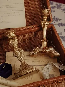 Close-up of matte gold baroque candle holders with ornate carvings in a retro setting