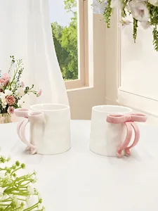 Detail view of cream ceramic mug featuring a 3D pink bow handle and wavy texture