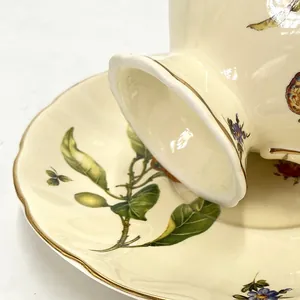Macro view of gold-rimmed ceramic cup with detailed vintage botanical flower print