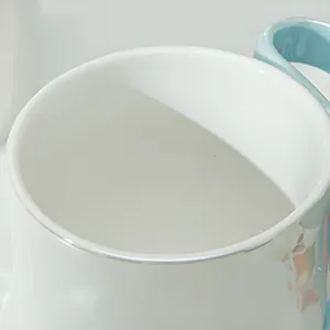 Vista macro di tazza in ceramica con bordo argento, manico azzurro e dettagli floreali