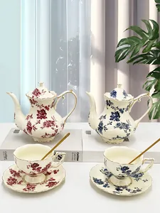 Dettaglio del set da tè vintage in ceramica con motivi floreali e bordo dorato su libri