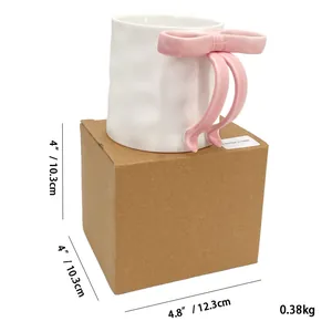 Detail of white handmade ceramic mug with pink 3D bow handle and packaging box dimensions