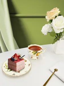 Detail of vintage ceramic tea set with citrus and berry motifs and gold-rimmed edges