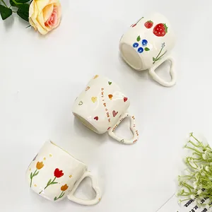 Drie keramische koffiemokken met hartvormige handgrepen en bloemmotieven op wit decor
