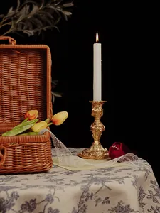 Detailed view of ornate golden baroque candlestick with lit candle and vintage props