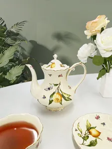 Detailed view of pastoral ceramic teapot set with lemon motifs and gilded golden edges