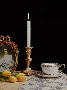 Baroque gold candlestick detail with intricate carving and a lit white candle