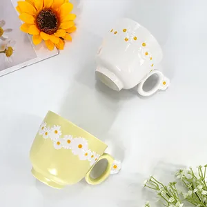 Handmade ceramic daisy coffee mugs with flower shaped handles in yellow and creamy white