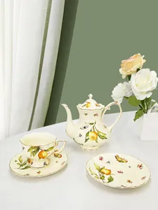 Detail of vintage ceramic tea set with golden rims, orange prints and butterfly motifs
