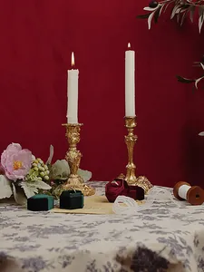 Close-up of golden Baroque candle holders with velvet jewelry boxes in vintage setting