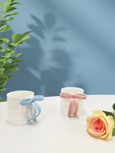 Close-up of creative ceramic mugs featuring 3D bow-shaped handles in pink and blue colors