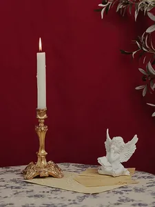 Baroque gold candle holder with white candle and angel statue on vintage tabletop décor