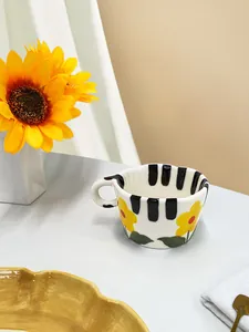 Detalle de taza de cerámica con diseño floral amarillo y asa con teclas de piano
