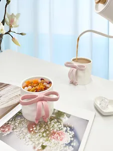 Detail of creative ceramic mug with 3D pink bow handle being filled with coffee