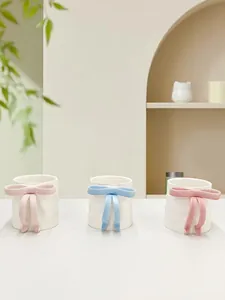 Detailed view of handmade 3D bowknot ceramic mug in pastel pink and cream white