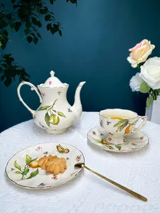 Detail of vintage ceramic tea set with ivory glaze, fruit patterns, and gold edges on lace