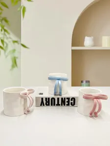 Close-up of cute 3D ceramic mugs featuring pastel pink and blue 3D bow handles