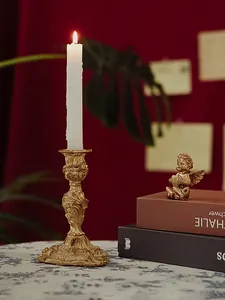 Detail of vintage gold Baroque candle holder with lit white candle on red velvet background