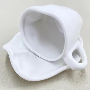 Top-down view of a white ceramic coffee cup and saucer with abstract face relief