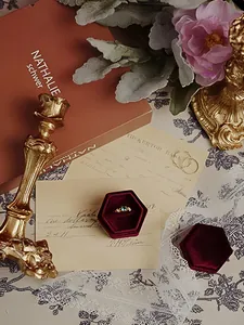 Golden ring with green emerald stone in a red velvet box with vintage candle holder