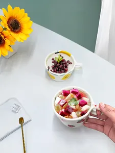 Vista superior de una taza de cerámica blanca con fresas pintadas a mano en una mesa
