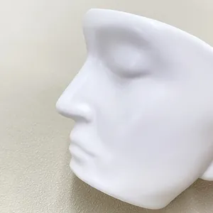 Close-up of minimalist white ceramic coffee cup featuring a creative face silhouette profile