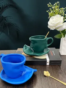 Artistic face relief ceramic coffee cup and saucer set with elegant gold spoon detail