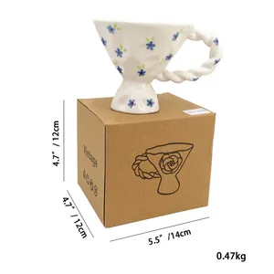 Close-up of vintage floral ceramic cup with twisted handle and product packaging box