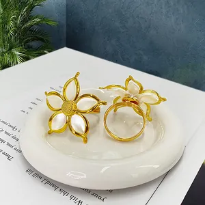 Dettaglio di portatovaglioli a forma di fiore bianco con base dorata per tavola elegante