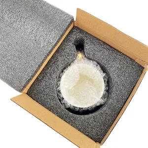 Detailed view of white floral ceramic cup with gold handle in protective foam packaging
