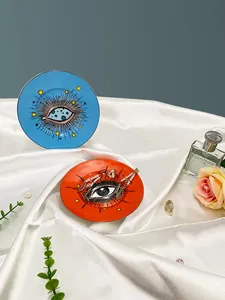 Détail des plateaux à bijoux en céramique œil bleu et orange sur un tissu en satin