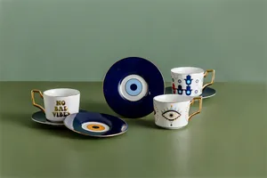 Dettaglio macro della tazzina da caffè Evil Eye con manico dorato e motivo Hamsa