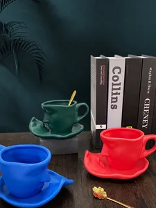 Artistic face relief ceramic coffee cup and saucer set in green, red, and blue colors