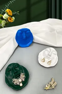 Detailed view of abstract face jewelry trays holding pearl earrings and gold brooches